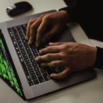 crop cyber spy hacking system while typing on laptop