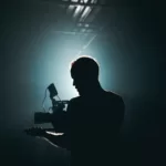 silhouette of man standing in front of microphone